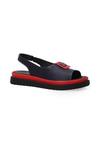 Sandały typu slingback w granatowej skórze z czerwoną akcentującą paskiem, otwarty przód, czarna podeszwa i dekoracyjne elementy na pasku.