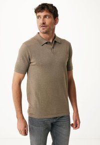 Kortärmad polo i en ljusbrun stickad tyg, med en klassisk krage, tvåknapps knäppning och subtila texturdetaile.