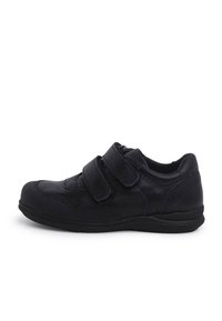 Scarpa sportiva nera con cinturini in velcro, pelle liscia e tessuto strutturato, punta arrotondata, suola bassa e dettagli di cucitura minimali.