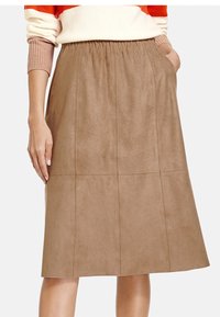 Ruskea nubuk midi-hame, jossa on joustava vyötärö, sivutaskut ja sileä rakenne, sekä pystysuorat ompelutiedot.