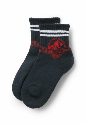 Schwarze Socken mit weißen Streifen am oberen Rand, versehen mit einem roten Jurassic World-Logo und einem Dinosaurier-Graphic auf dem Bund.