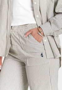 Gestreepte katoenen loungewear set in beige en marineblauw, met een overhemd met knopen en een broek met elastische tailleband, zijzak en logo-detail.