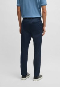 Navy blue trousers with a straight design, featuring side pockets, belt loops, and a smooth fabric texture. Worn with a light blue shirt.