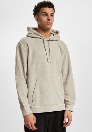 Beige, ribbet genser med kengurulomme, snorhette og teksturert stoff. Har lange ermer og en avslappet passform.