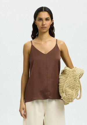 Top sin mangas plisado marrón con diseño de escote en V, combinado con un bolso tejido de color claro. Textura suave y ajuste relajado.