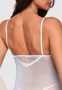 Bodysuit blanco transparente con delicados bordes de encaje en la parte posterior, tirantes finos y una textura suave. Enfocándose en los detalles sutiles en el diseño.