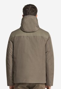 Puffjacka i olivgrön med hög krage, texturerade axeldetaljer och en slät yta. Bakvy som visar en avslappnad passform och minimal detaljering.