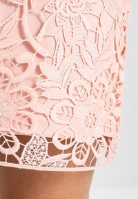 Light pink skirt featuring intricate floral lace embroidery with scalloped edges and layered texture, highlighting detailed flower patterns.