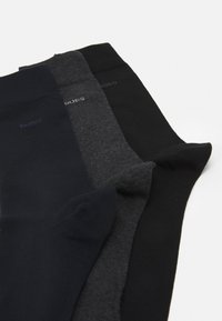 Tre par sokker i mørke farver: en marineblå, en kullgrå og en sort. Glat tekstur med forstærkede tåområder og elastiske manchetter.