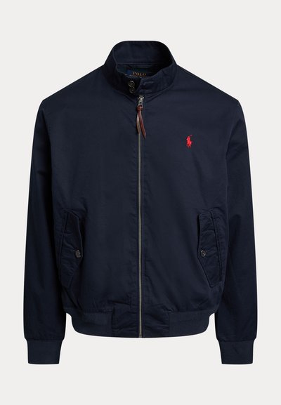 Veste bleu marine zippée avec col montant, deux poches boutonnées, poignets et ourlet côtelés, et un petit logo rouge représentant un cheval.