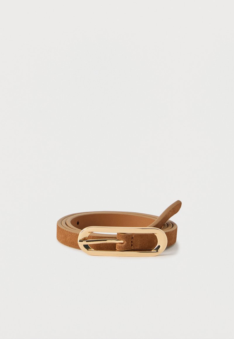 Ceinture en daim couleur noisette enroulée avec une boucle allongée en métal doré brillant, posée sur un fond blanc.