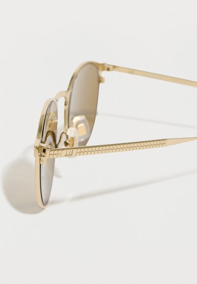 Γυαλιά ηλίου με μεταλλικό χρυσό σκελετό, υφασμένες βραχίονες και φακούς καφέ απόχρωσης, με την επωνυμία «dunhill» στη βραχίονα.