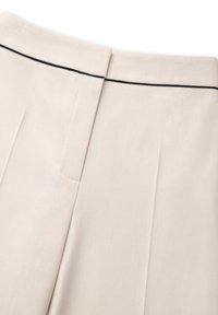 Beige linnen broek met een zachte textuur, plooien aan de voorkant en een zwarte accentlijn langs de tailleband.