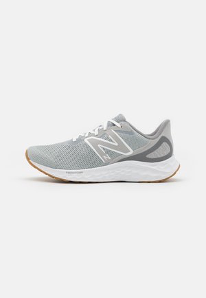Chaussure de course en mesh gris clair avec des lacets blancs, une semelle intermédiaire blanche étiquetée Fresh Foam, et une semelle extérieure en caoutchouc marron.