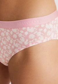 Rosa blommönstrade bomullsunderkläder med en mjuk, elastisk rosa midjeelastik som har präglad logotyp. Slät textur och figurnära design.