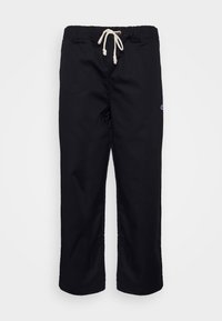 Pantalon décontracté noir avec taille élastique et cordon blanc, jambes droites et petit logo sur la cuisse droite.