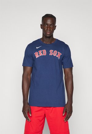 Camiseta de algodón azul marino con la inscripción "RED SOX" en letras rojas, cuello redondo, mangas cortas y un pequeño logo blanco de Nike en el lado izquierdo del pecho.