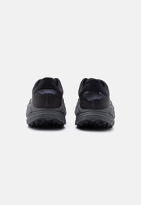 Ζευγάρι από μαύρα και γκρι παπούτσια για τρέξιμο σε μονοπάτι, εμφανιζόμενα από πίσω σε λευκό φόντο, με έμφαση στις ανθεκτικές σόλες και τα επενδυμένα πέλματα.