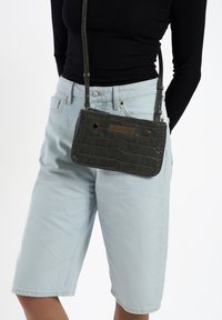 Donkergroene, faux krokodillenleren schoudertas met een gestructureerde vorm, textuur op het oppervlak, gouden accenten en een verstelbare strap.