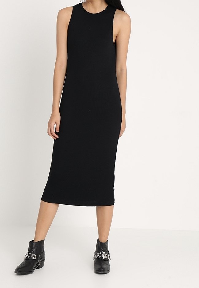 Czarna ribbedowa dzianinowa sukienka bez rękawów, dopasowany fason o prostym kroju, zestawiona z czarnymi botkami za kostkę z dekoracyjnymi elementami.