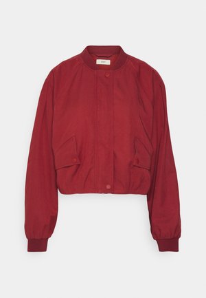 Krótkia czerwona kurtka bomberka z okrągłym dekoltem, zatrzaskami, bocznymi kieszeniami i elastycznymi mankietami. Wykonana z gładkiego, lekkiego materiału.