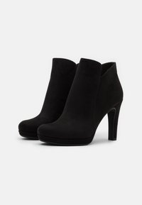 Bottes noires en suede à chevilles avec un bout fermé, texture lisse et talon haut, présentant un design élégant et épuré sans embellissements.