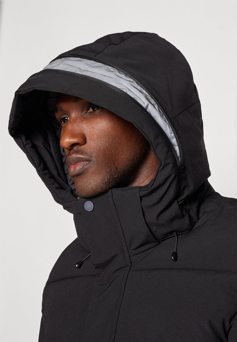 Schwarze Kapuzenjacke mit strukturiertem Außenmaterial, verstellbaren Kordeln und einem kontrastierenden grauen Futter. Mit Knopfverschluss.