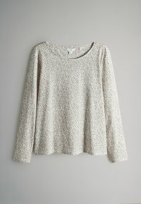 Długo rękawowy top z miękkiego materiału, w beżowym kolorze z przypadkowymi brązowymi plamkami w motyw panterki. Okrągły dekolt i luźny krój.