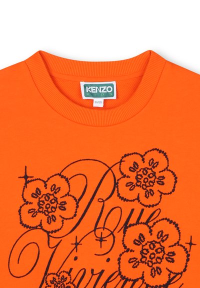T-shirt en coton orange avec un design floral noir et du texte en script. Encolure ronde côtelée, manches courtes et texture douce.