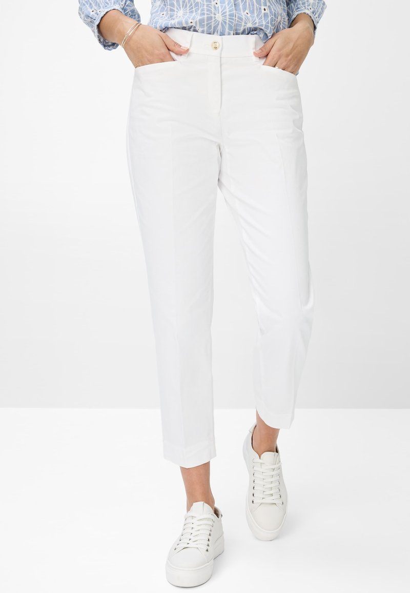 Pantaloni bianchi a sigaretta con tasche laterali, vita alta e chiusura con bottone. Abbinati a sneaker bianche, con tessuto liscia e design pulito.