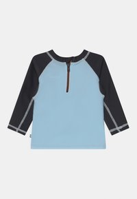 Rash guard de mangas longas azul e preto com fecho à frente, apresentando costura cinza e um detalhe laranja no pescoço.