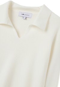 Maglione bianco a coste con scollo a V e colletto a punta. Presenta un'etichetta con la scritta "B ANGEL". Tessuto morbido e design leggero.