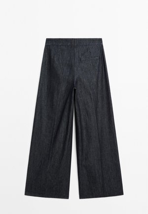 Pantalon en denim à jambes larges de couleur bleu foncé, avec une texture lisse, une poche arrière et un motif vertical subtil. Comprend une ceinture élastique.