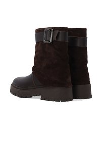 Brązowe zamszowe botki za kostkę z teksturowanym wykończeniem, z szerokim skórzanym paskiem i akcentem w postaci klamry. Gruba gumowa podeszwa zapewniająca stabilność.
