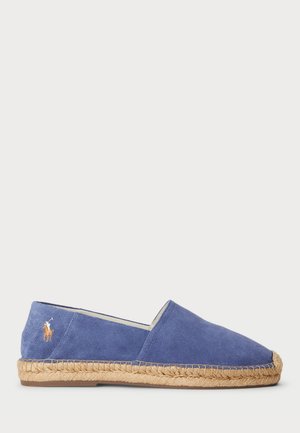 Espadrille en daim bleu avec une semelle en jute tissée, arborant un petit logo brodé sur le côté et un design à enfiler.