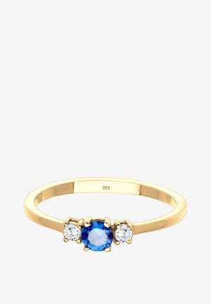 Guldbelagt sølvring med en central blå ædelsten, flankeret af to klare ædelsten, med en glat, rund skæft.