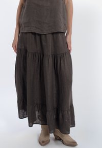 Bruine linnen rok met gelaagde tiers en een gerimpelde zoom. Gecombineerd met beige cowboylaarzen. Gladde textuur, ontspannen pasvorm, lengte tot halverwege het scheenbeen.