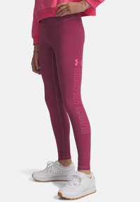 Tajta, högmidjade leggings i en livlig magentafärg. Har en vertikal "UNDER ARMOUR"-logga i en ljusare nyans längs sidan.