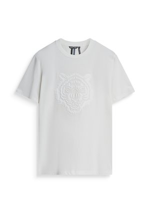 Camiseta blanca de algodón con un diseño de cara de tigre texturizado y en relieve en el pecho. Manga corta y escote redondo.