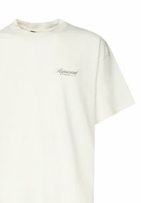Camiseta de algodón blanca con cuello redondo y mangas cortas. Presenta un pequeño logo impreso en verde oscuro en el lado izquierdo del pecho. Textura suave.