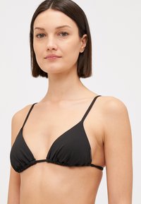 Crni bikini gornji dio s trokutastim dizajnom, nabranym materijalom i tankim podesivim trakama. Izrađen od glatkog, rastezljivog materijala.