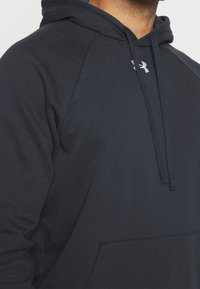 Sweatshirt gris foncé avec capuche, doté d'une poche kangourou, de poignets côtelés et du logo Under Armour en blanc. Tissu doux et texturé.