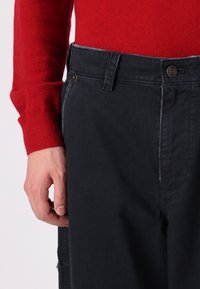 Dark blue denim pants with a straight cut, featuring a top button closure, belt loops, and a contrasting stitch along the seams.