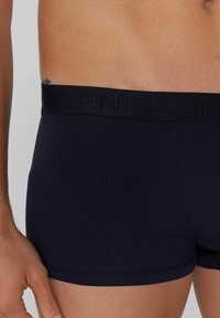 Navy modré boxerky mají jednobarevný design, měkkou texturu a široký černý elastický pas s embosovaným brandingem na horní části.