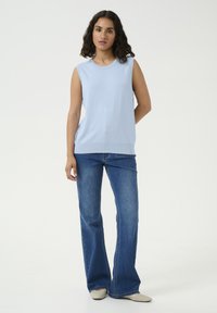 Haut sans manches bleu clair avec un col rond, associé à un jean bleu évasé. Texture douce, tissu lisse et design simple.