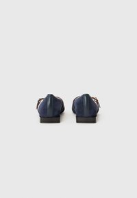 Mocassini in suede blu navy con tacco in pelle liscia e suole in gomma leggere. Nessun motivo o dettaglio hardware visibile.