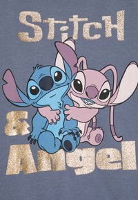 Siva majica s plavimi in roza risankami, Stitchom in Angelom, ter z zlatim bleščečim napisom "Stitch & Angel" spodaj.