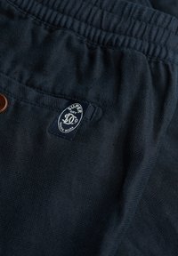 Marineblaue Shorts aus strukturiertem Stoff mit elastischem Bund und einem kleinen Logolabel auf der vorderen Tasche.