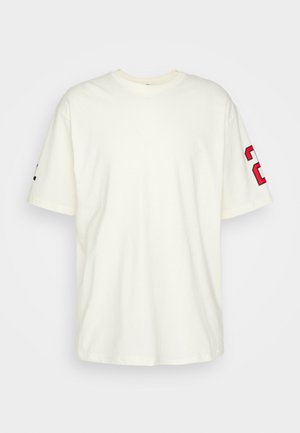 Jednoduché biele tričko s krátkym rukávom a červeným a čiernym číslom "23" potlačeným na pravom rukáve na bielom pozadí.