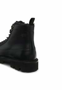 Stivale in pelle nera alla caviglia con una fodera texturizzata e soffice, punta rotonda e suola robusta. Presenta chiusura con lacci e linguetta sul retro.